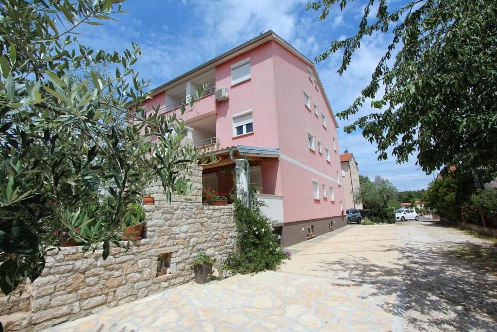Vanjski izgled ružičaste kuće s istarskim kamenim zidom i parkiralištem, Apartments Ulika Rovinj
